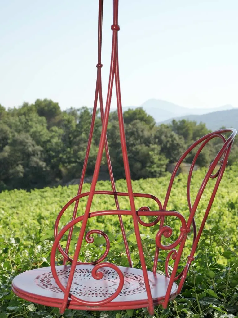 Pair of hanging red metal swings from the oak tree